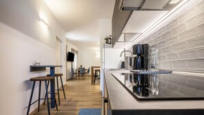 A modern kitchen with a long countertop, bar stools, a coffee machine, and a TV mounted on the wall. - Apartment "Casa Chiarani" with Mountain View, Balcony and Wi-Fi (Arco)