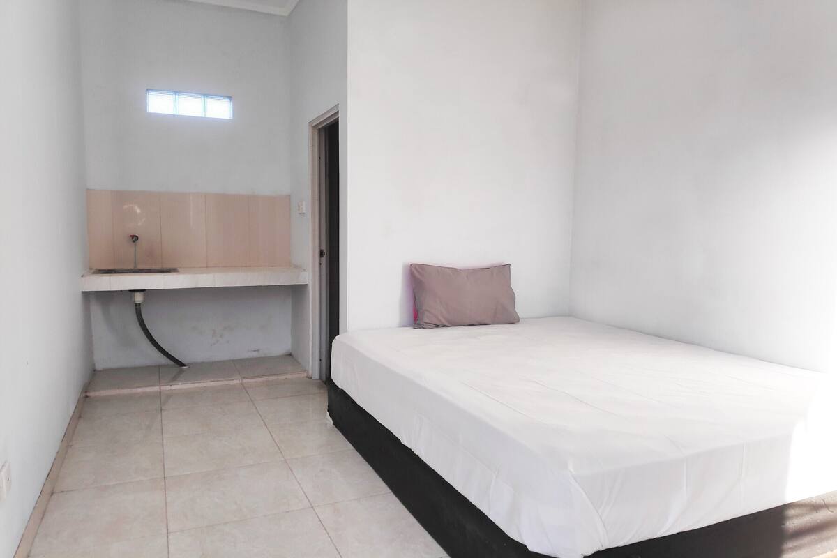 A small, clean room with a single bed, a desk, and a window.