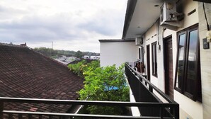 Een balkon met uitzicht op omliggende gebouwen en een boom.