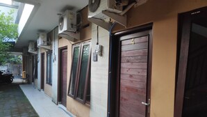 Een gebouw met meerdere deuren, waarvan sommige voorzien zijn van glaspanelen en andere van massieve houten deuren, met airconditioningsapparaten aan de buitenmuren bevestigd.