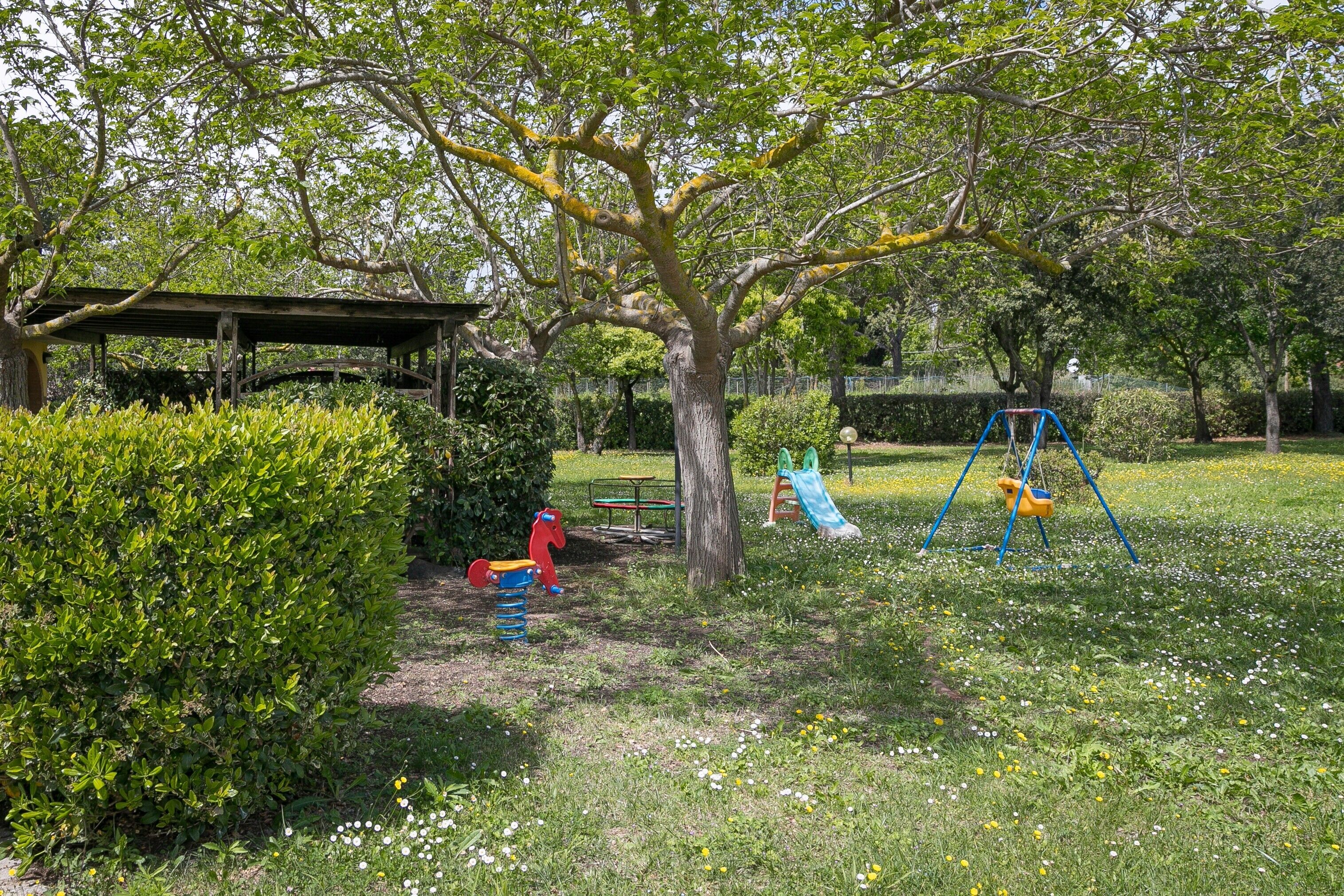 A park with a swing set, a slide, and a covered seating area.
