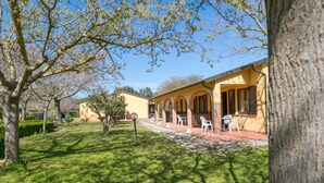 A building with a yellow facade, arched windows, and a paved patio area with outdoor seating. - Farmhouse "Il Girasole - Limone" with Shared Pool, Shared Garden & Wi-Fi (Venturina Terme)