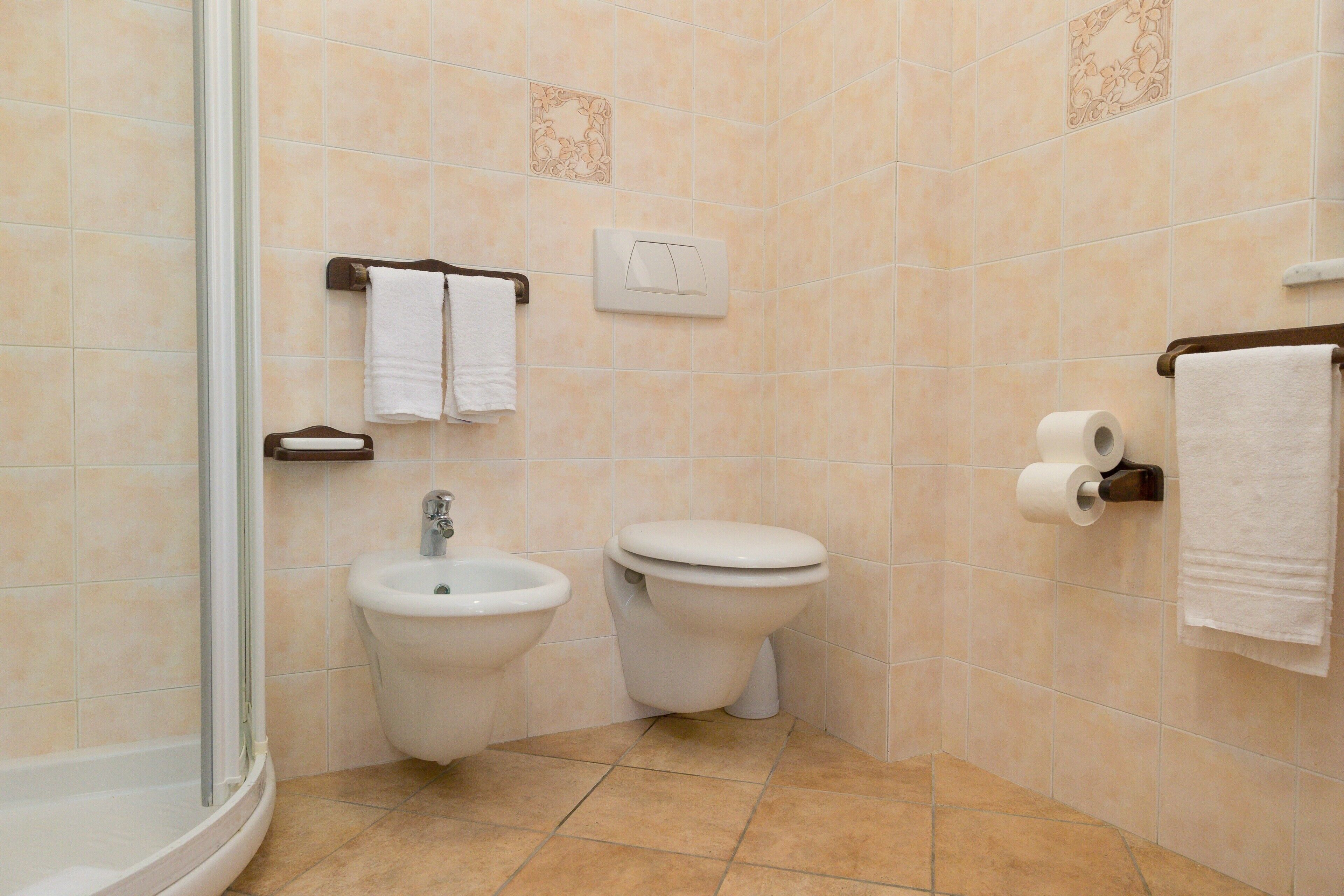 Un baño con ducha, bidé, inodoro y toallero.