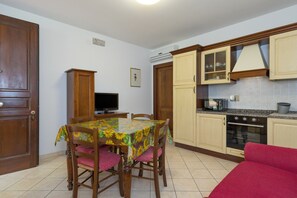 Una cocina compacta con una mesa de comedor, sillas, un televisor y un sofá rojo.