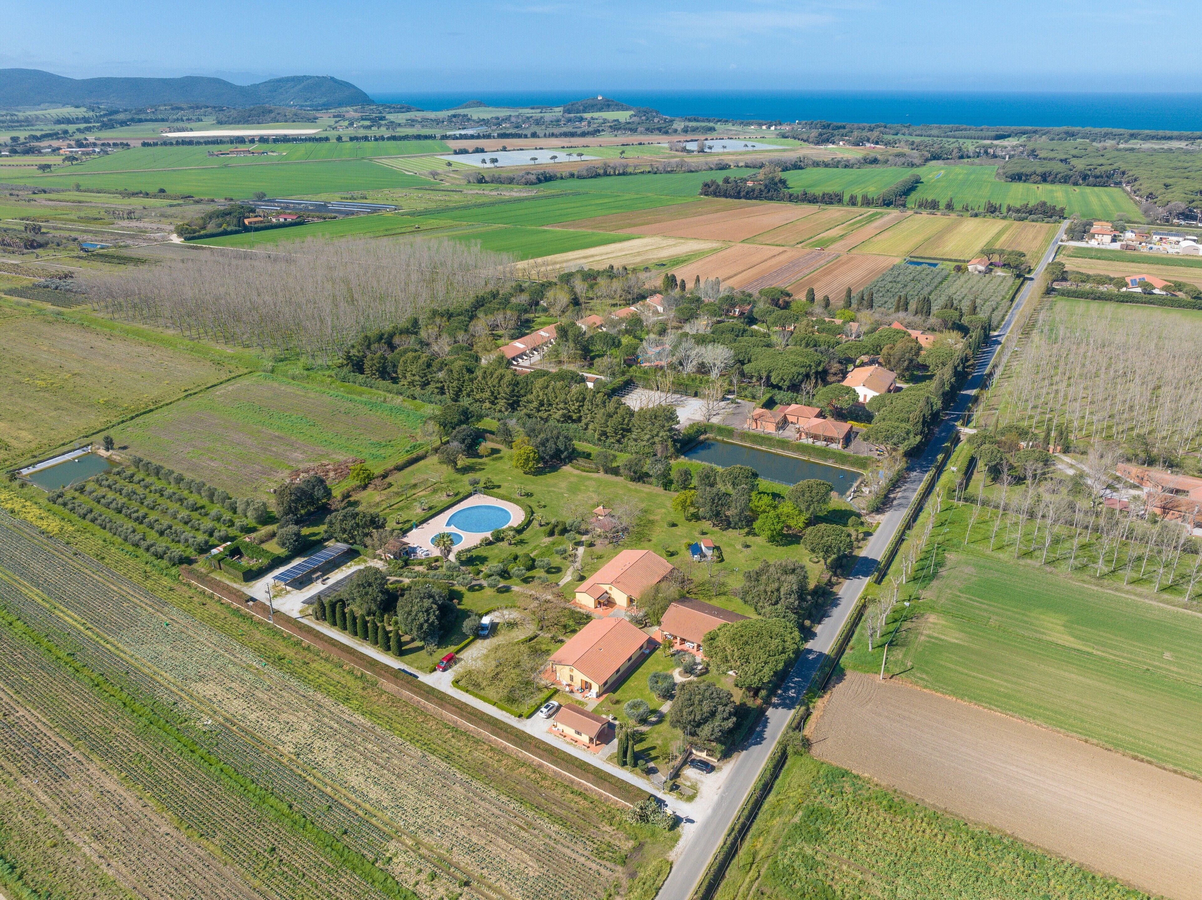 Vue aérienne d’une propriété rurale avec des champs, une piscine et plusieurs bâtiments.