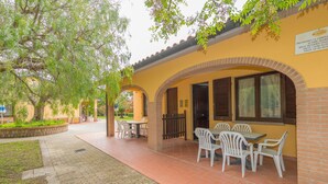Un patio al aire libre con mesas y sillas, un camino de ladrillo y un edificio amarillo con un letrero.