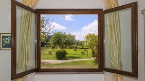 Una stanza con un'ampia finestra, tende e un quadro appeso al muro.