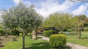 Un giardino con un vialetto lastricato, una scultura in pietra e un'area giochi.