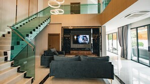 Ein modernes Interieur mit einer Treppe, einem Wohnbereich inklusive Sofa und einem Fernsehbildschirm.