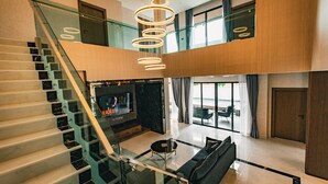 Ein modernes Interieur mit Treppe, einer Wohnbereich mit Sofa und Couchtisch sowie einem großen Fenster mit Aussicht.