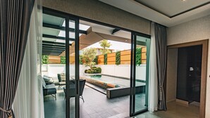 Ein modernes Interieur mit einer Glastür, die auf eine Patio mit Pool, Gartenmöbeln und Blick auf die umliegende Nachbarschaft führt.
