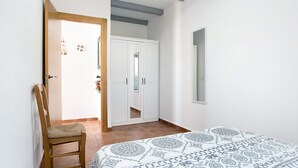 Ein Schlafzimmer mit einem Bett, einem Kleiderschrank, einem Sessel und einem Spiegel.