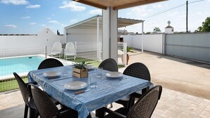 Eine Außenpatio mit Esstisch, Pool und überdachtem Sitzbereich.