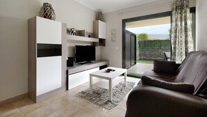 A modern living room with a flat-screen TV, a white coffee table, and a brown sofa.
