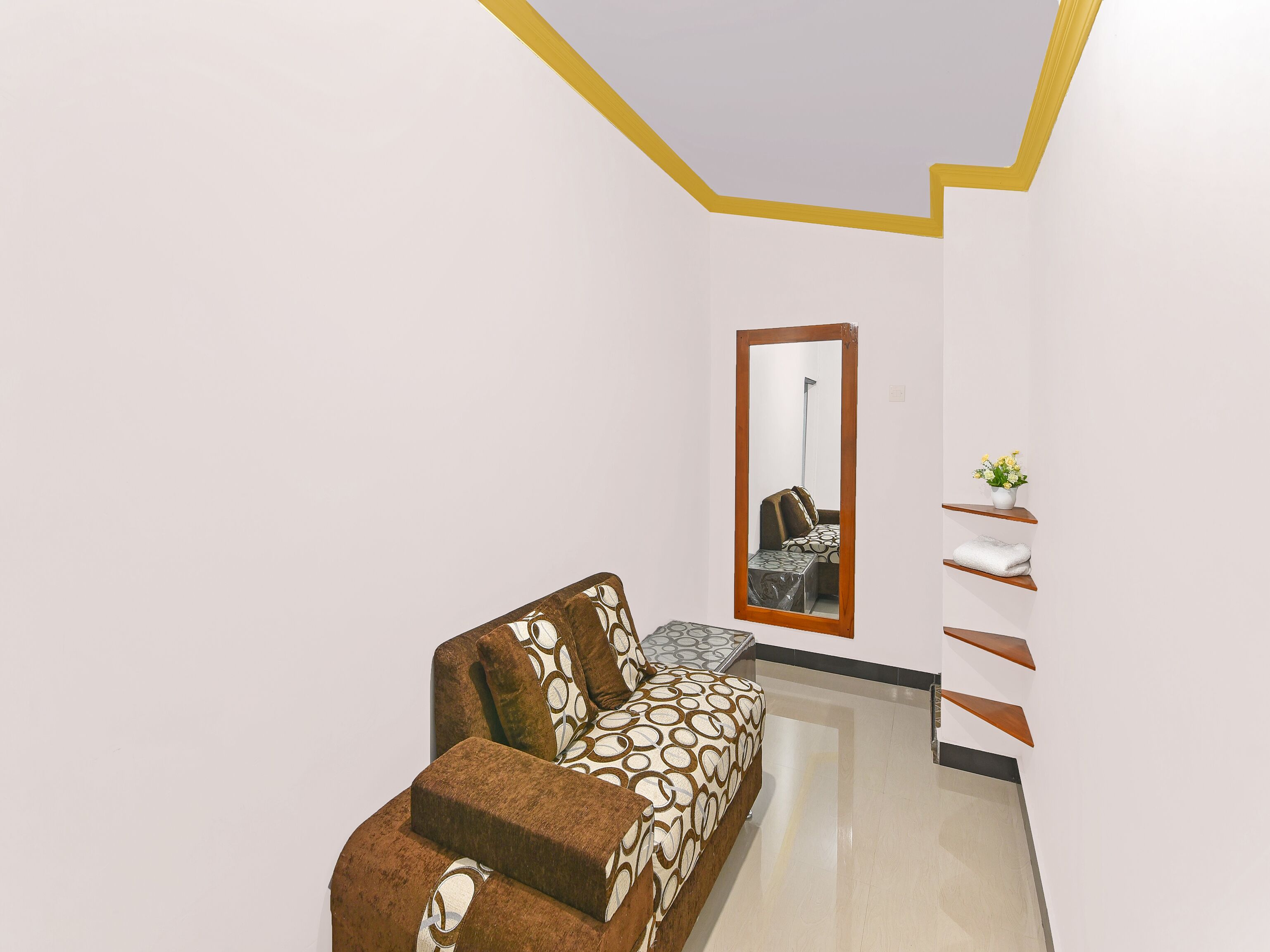 A modern interior with a sofa, a mirror, and a small plant.
