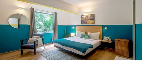 Une chambre à coucher comprenant un lit, une chaise, une table de chevet, une lampe, un miroir et une fenêtre avec des rideaux.