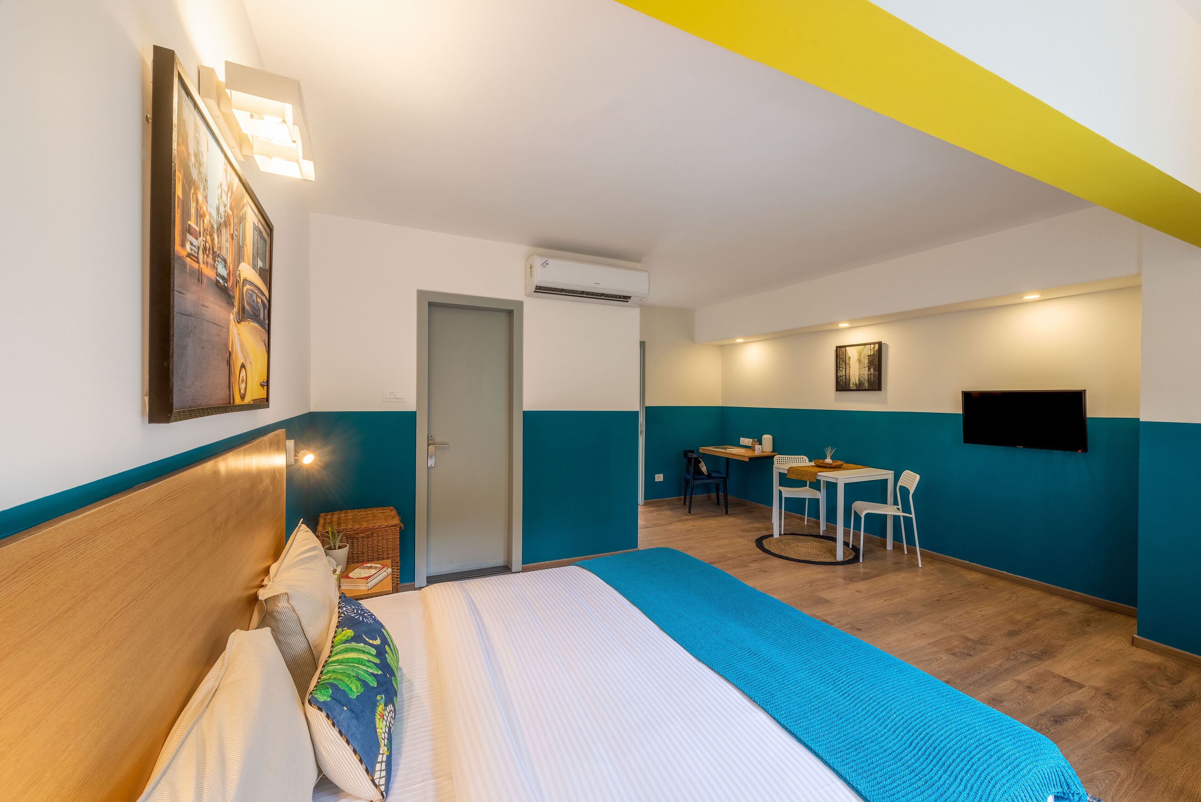 Ett hotellrum med en säng, ett skrivbord, en stol, en tv och en luftkonditioneringsanläggning.