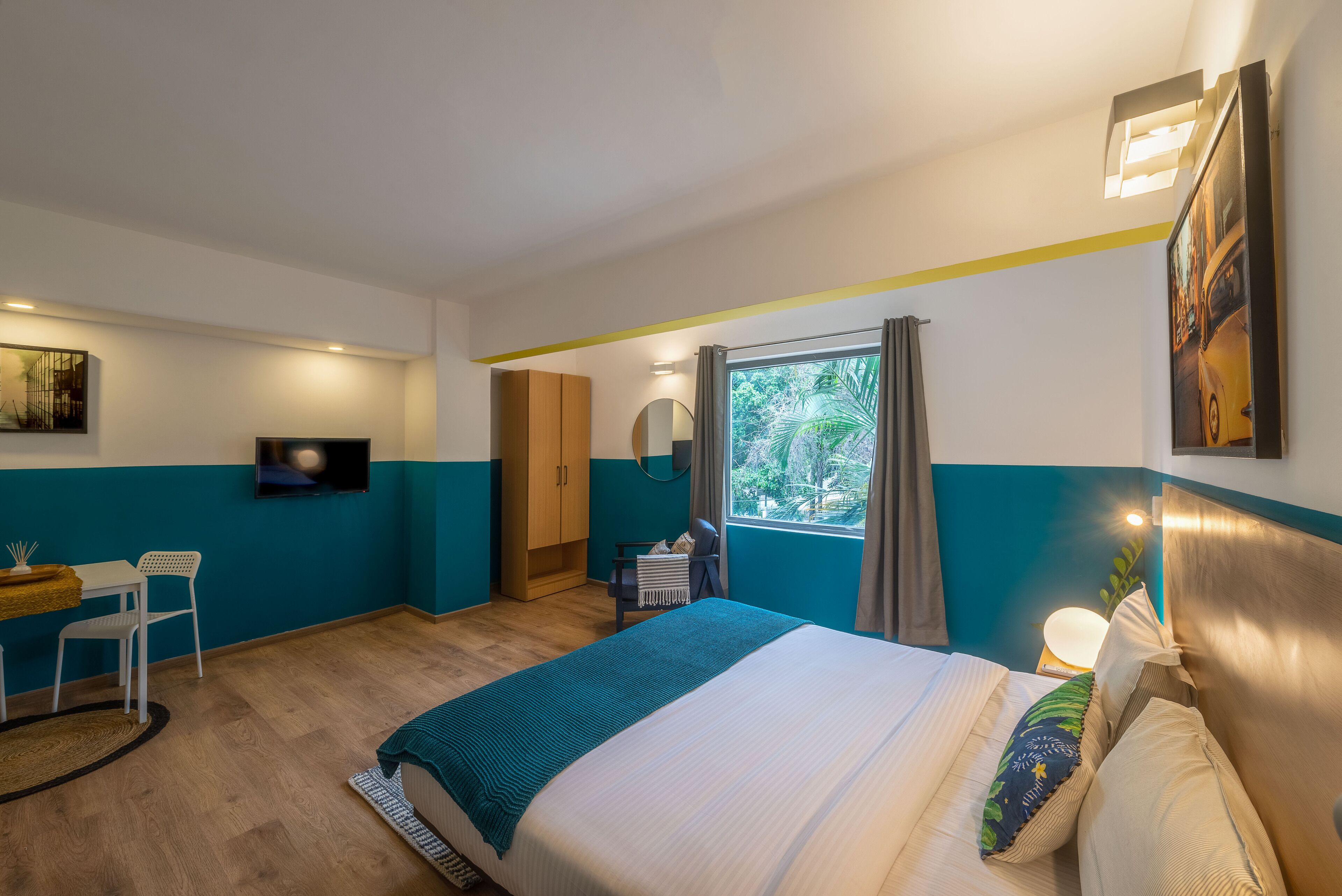 Un dormitorio con cama, escritorio, silla, televisor y ventana con cortinas.