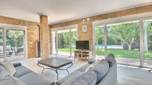 A spacious living room with a large TV, comfortable seating, and a view of a backyard with a pool. - Modern villa in Las Rotas with air conditioning (Denia)