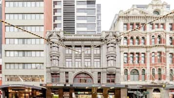 Een historisch gebouw met een klassiek gevelontwerp, een opvallende boogvormige ingang en een moderne etalage eronder.