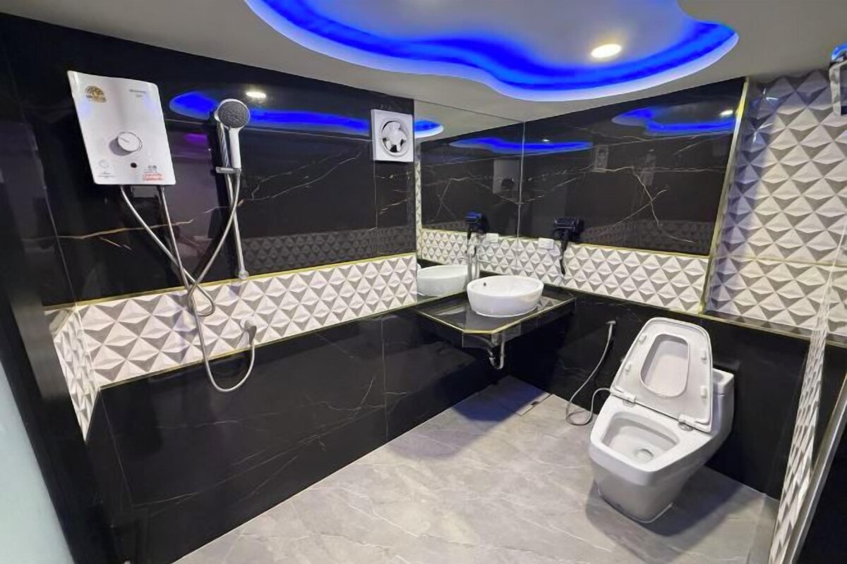 A modern bathroom with a black and white marble design, a toilet, a bidet, and a sink.