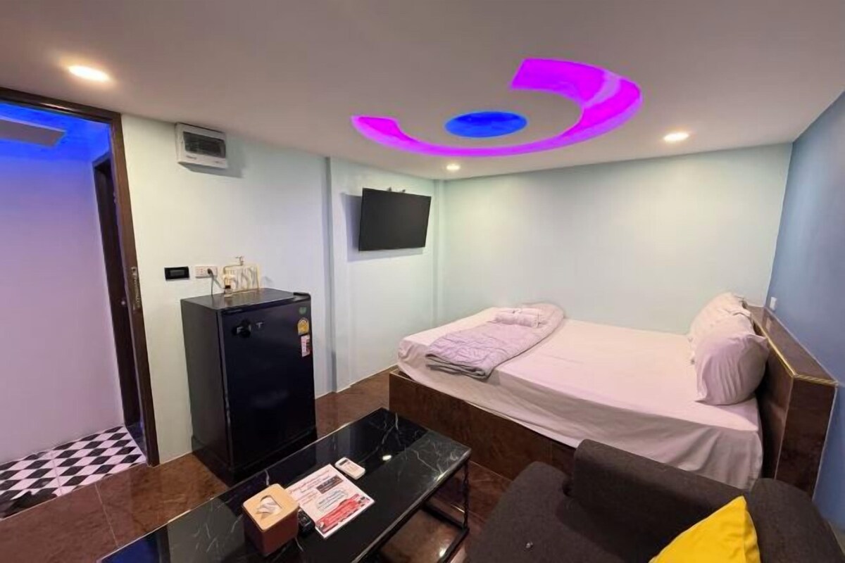 A hotel room with a bed, a desk, a TV, and a minibar.