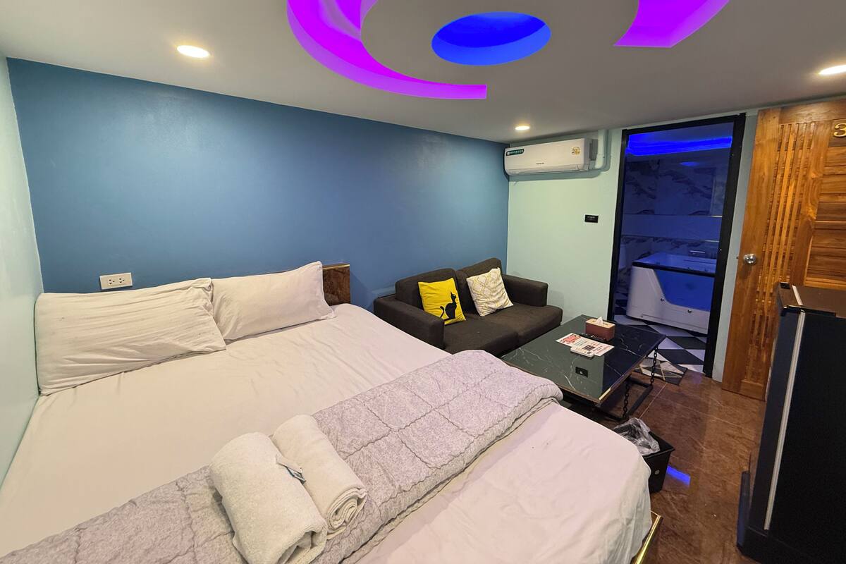 Une chambre d’hôtel avec un lit, un canapé, une petite table et un luminaire au plafond.