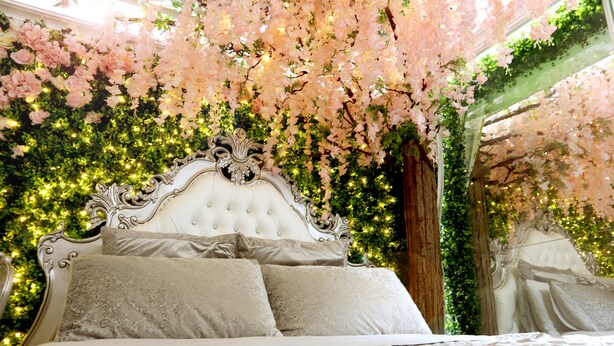 A luxurious bed with a tufted headboard, surrounded by lush greenery and pink flowers. - Secret Garden - A Magical Themed Studio in the heart of Melbourne CBD (Melbourne,)