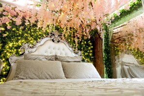A luxurious bed with a tufted headboard, surrounded by lush greenery and pink flowers. - Secret Garden - A Magical Themed Studio in the heart of Melbourne CBD (Melbourne,)