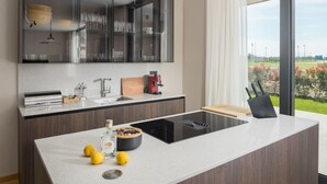 A modern kitchen with a central island, a built-in oven, and a large window offering a view of the outdoors.