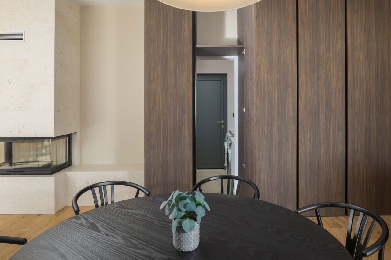 A modern dining area with a round table, chairs, and a potted plant.