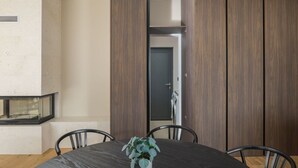 A modern dining area with a round table, chairs, and a potted plant.