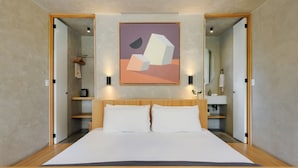 Ein modernes Schlafzimmer mit einem großen Bett, einem hölzernen Kopfstück und einem Bild darüber.