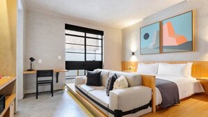 Une chambre d’hôtel moderne équipée d’un canapé-lit, d’un bureau et d’une grande fenêtre.