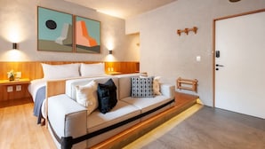 Une chambre d’hôtel moderne équipée d’un lit, d’un canapé, d’une table de chevet en bois et d’une porte.