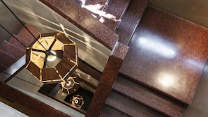 Un escalier moderne surmonté d’un luminaire aux formes géométriques.