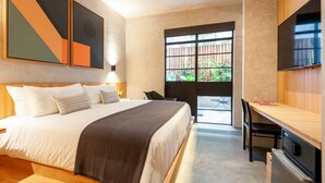 Une chambre d’hôtel avec un lit, un bureau, une télévision et une grande fenêtre.