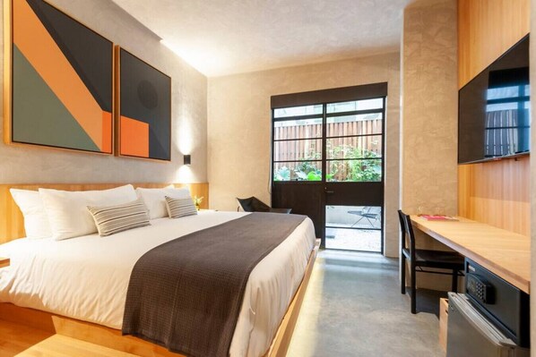 Une chambre d’hôtel avec un lit, un bureau, une télévision et une grande fenêtre.