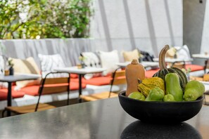 Un bol de légumes est posé sur une table dans un restaurant. Les sièges sont rembourrés de rouge et un mur blanc se trouve à l’arrière-plan.