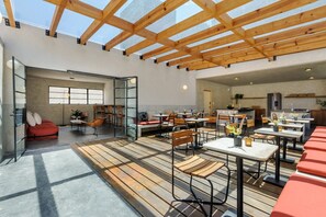 A spacious indoor area with a high ceiling, wooden beams, and a mix of seating arrangements including tables and chairs. - Astonishing studio w/terrace @Parque Mexico | Chico (Ciudad de México)