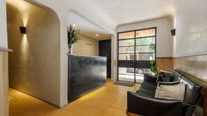 Un área de recepción con diseño moderno, que incluye un mostrador de recepción, una zona de estar con sofá y sillones, y un amplio ventanal hacia el exterior.