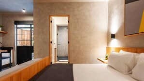 Une chambre d’hôtel moderne, dotée d’un grand lit, d’un bureau et offrant une vue sur l’extérieur.
