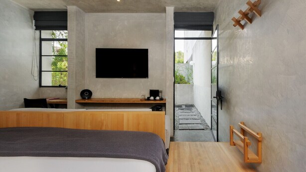A modern bedroom with a large bed, a flat-screen TV, a wooden desk, and a small seating area. - Studio with Terrace next to Parque Mexico | ChiCo (Ciudad de México)