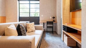 Un espace de vie compact comprenant un canapé, un petit bureau, une chaise et un téléviseur.