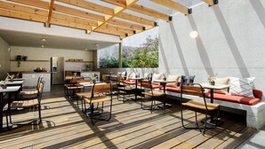 Une terrasse extérieure dotée d’un plancher en bois, d’espaces aménagés pour s’asseoir et d’un coin cuisine.