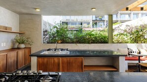 An outdoor kitchen with a gas stove, sink, and wooden cabinets. - Wonderful apt w/ balcony @Parque Mexico | ChiCo (Ciudad de México)