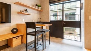 A compact kitchen with a wooden countertop, two black chairs, a coffee machine, and a TV mounted on the wall. - Wonderful apt w/ balcony @Parque Mexico | ChiCo (Ciudad de México)