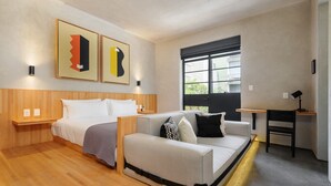 Quarto de hotel moderno com cama, sofá, escrivaninha e janela com vista.