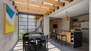 Une cuisine moderne dotée d’un îlot central, de poutres en bois au plafond et d’une grande fenêtre.