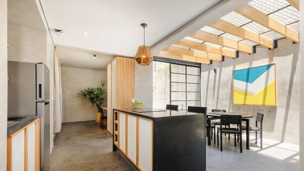 Une cuisine moderne dotée d’un îlot central, de meubles en bois et d’un coin repas avec une table et des chaises.